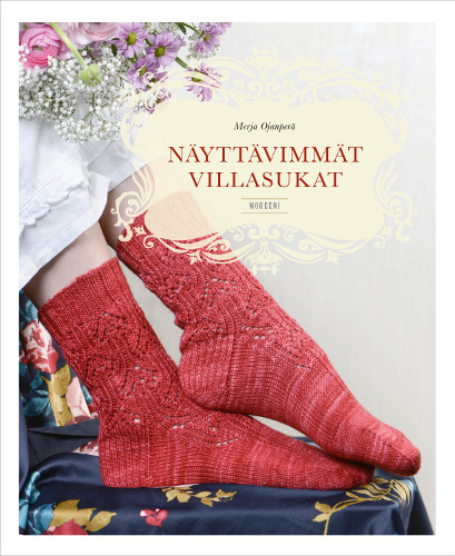 N&auml;ytt&auml;vimm&auml;t villasukat -neuleohjekirjan kansikuva, jossa punas&auml;vyiset pitsineulesukat henkil&ouml;n jaloissa.