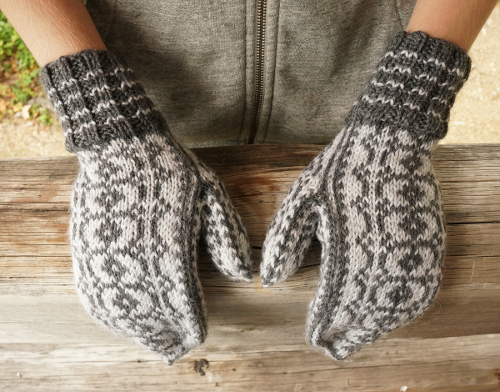 Valkoharmaat Riimu-kirjoneulelapaset henkil&ouml;n k&auml;siss&auml;