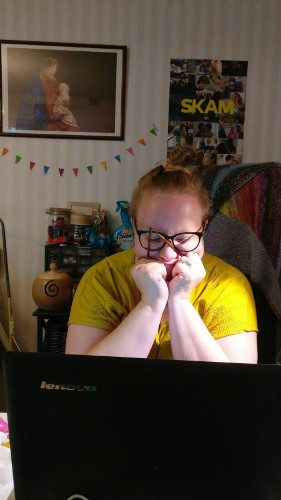 Keltapaitainen, silm&auml;lasip&auml;inen neuloja katselee l&auml;pp&auml;rin ruutua nojaten leukaansa puikkoja piteleviin k&auml;siins&auml;.