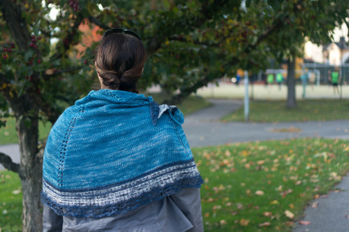 Asperitas-huivi kiedottuna selin seisovan naisen hartioille